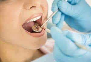 A woman's mouth being examined by a dentist.